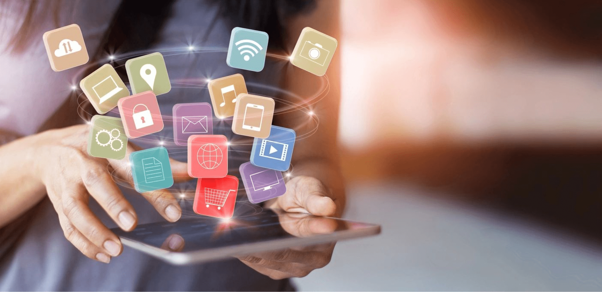 A person using a tablet with colorful digital app icons floating above the screen, symbolizing connectivity and technology.